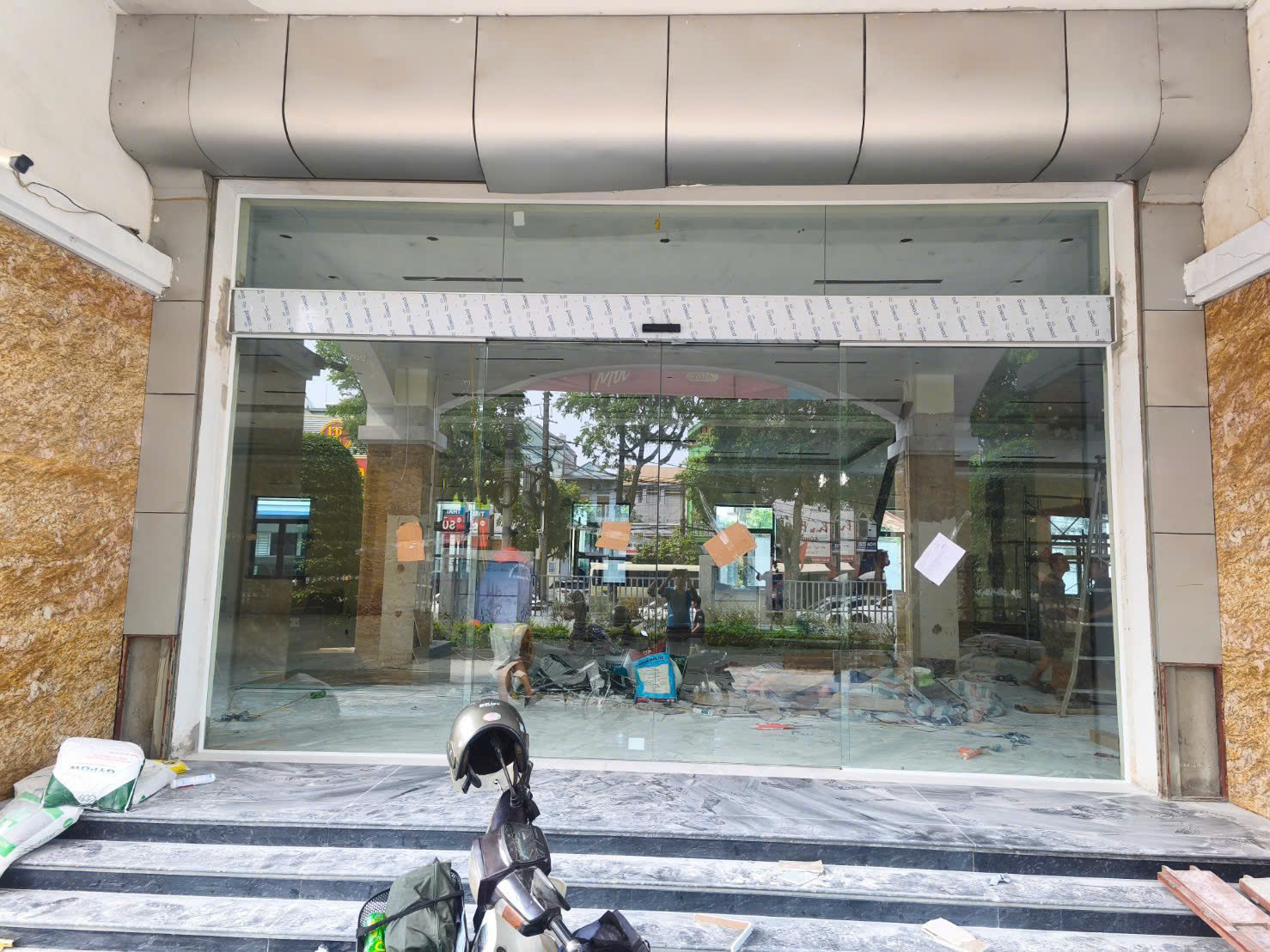 Cửa kính cường lực mặt tiền cửa hàng đang thi công với khung nhôm và bậc tam cấp đá marble